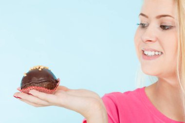 Çikolatalı kek tutan kadın ısırmak üzere.