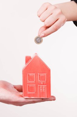 İnsanlar elleriyle küçük ev ve gümüş sikke.