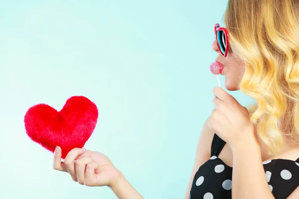 Mujer sostiene corazón rojo símbolo de amor y caramelo piruleta — Foto de Stock