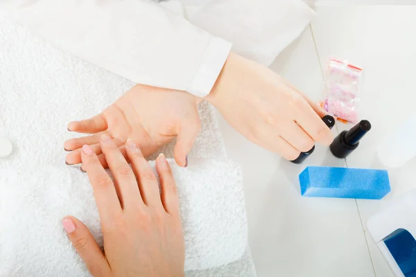 Woman hand on towel, next to manicure set — Stock Photo, Image