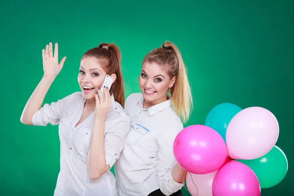 Dos chicas con teléfono móvil y globos —  Fotos de Stock