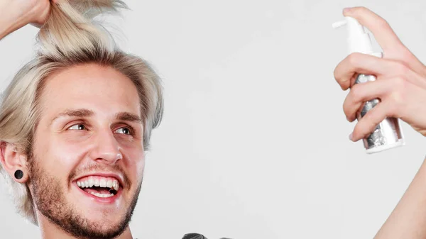 Hombre aplicando spray cosmético a su cabello — Foto de Stock