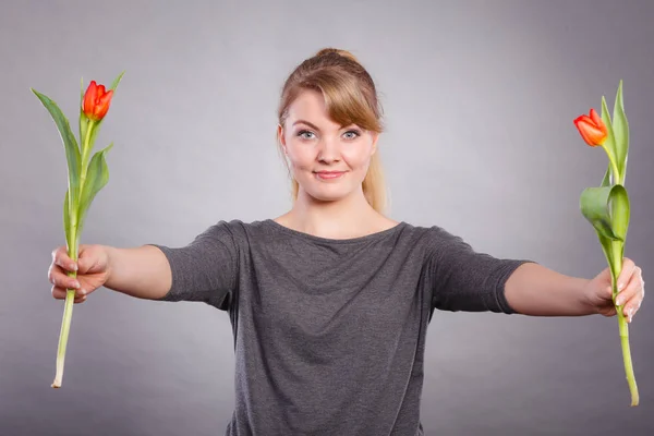 Speels meisje met plezier met bloemen tulpen. — Stockfoto