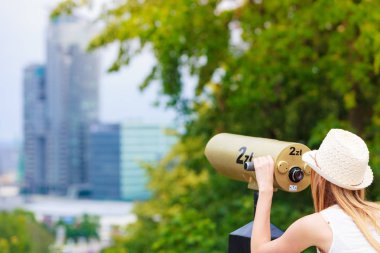 Teleskopla bakarak güneş şapkalı kadın turist