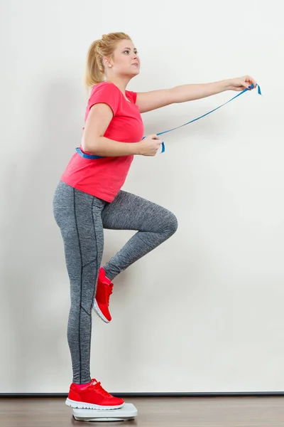 Woman wearing sportswear standing on weight machine — Stock Photo, Image