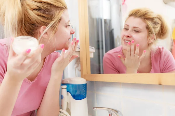 Mulher aplicando creme facial com o dedo — Fotografia de Stock