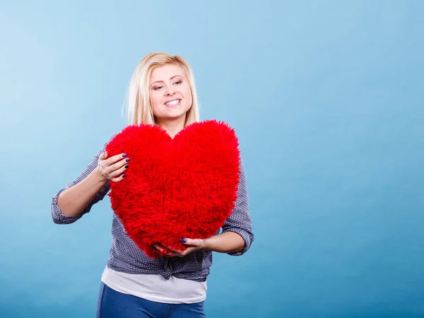 Mujer feliz sosteniendo almohada roja en forma de corazón —  Fotos de Stock