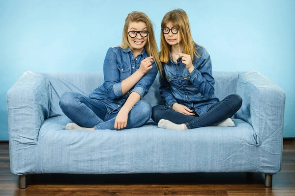 Deux femmes heureuses tenant de fausses lunettes sur le bâton — Photo