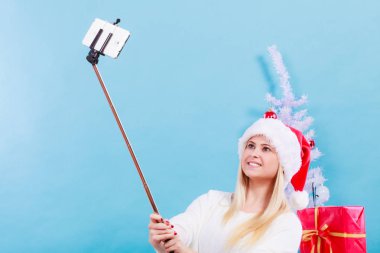 Santa şapka alarak fotoğrafını selfie stick kullanarak kız