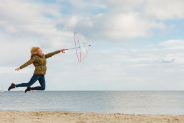 Kadın ile şeffaf şemsiye plajda atlama