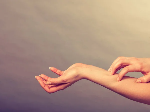 Женщина чешет свою зудящую руку аллергической сыпью — стоковое фото
