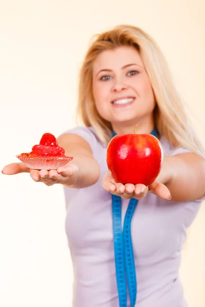 Woman with measuring tape choosing what to eat — Stock Photo, Image