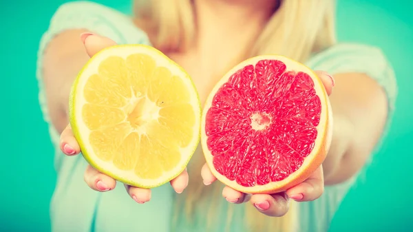 Halfs of yellow red grapefruit citrus fruit in human hands