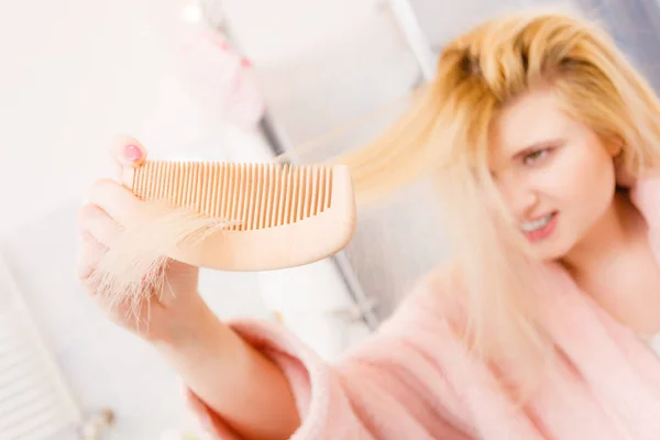 Потрясенная женщина в халате расчесывает волосы — стоковое фото