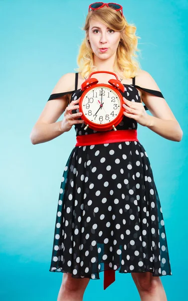 Blond meisje met wekker op blauw. — Stockfoto