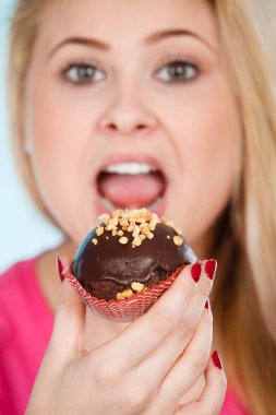 Çikolatalı kek tutan kadın ısırmak üzere.