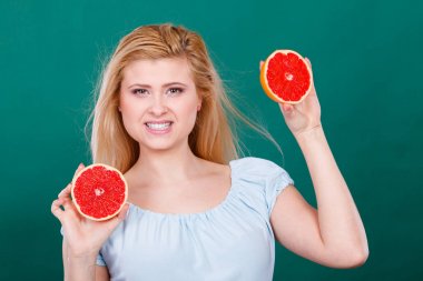 Kadın gülümseyen kız kırmızı greyfurt iki halfs narenciye meyve ellerinde yeşil holding. Sağlıklı bir diyet yemek. Yaz tatil kavramı eğlenceli.