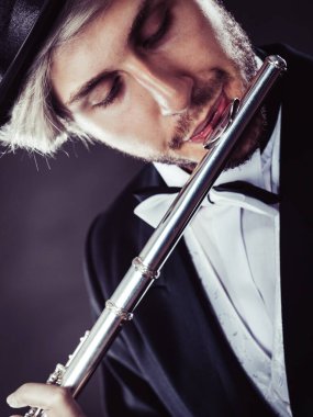 Zarif giyimli erkek müzisyen flüt çalmaya