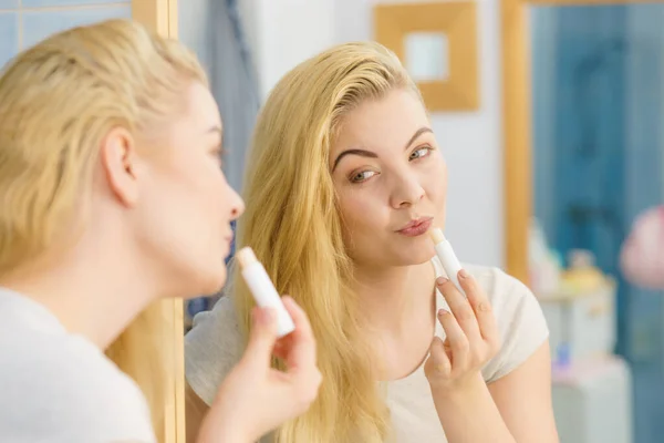 Mujer en baño aplicando bálsamo labial — Foto de Stock