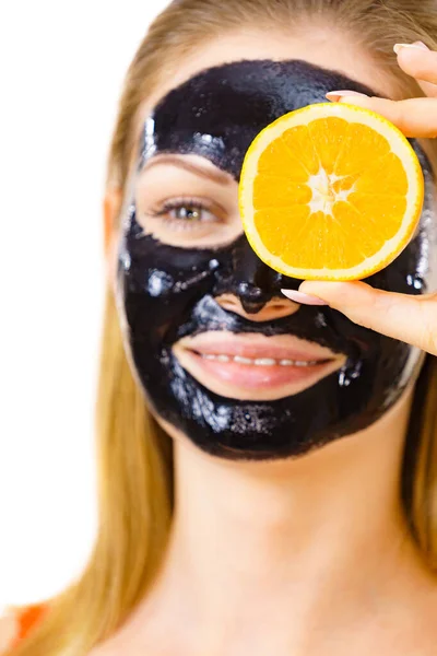 Girl black carbo mask on face holds orange fruit — Stok Foto