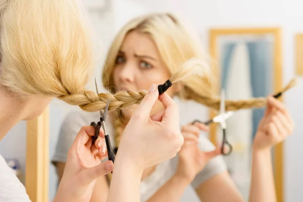 Woman cutting blond braid hair — Stock Photo, Image