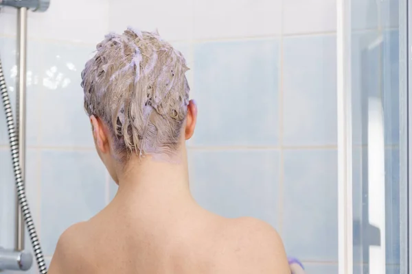 Kvinna i duschen med färgat skum på hår — Stockfoto