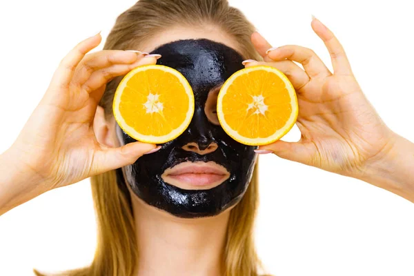 Girl black carbo mask on face holds orange fruit — Stok Foto