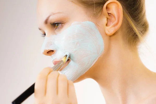 Girl apply green mud mask to face