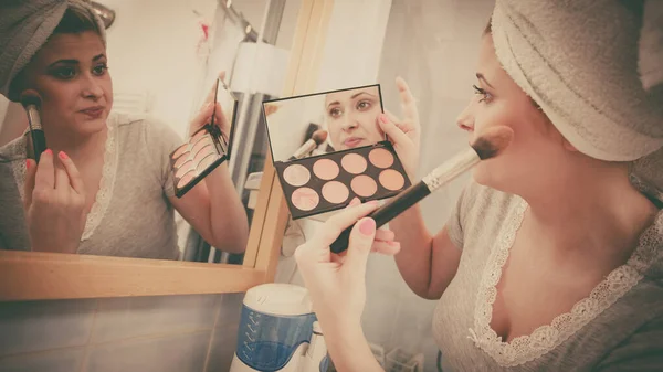 Woman in bathroom applying contour bronzer on brush — Stock Photo, Image