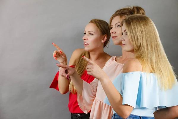 Three fashionable females pointing