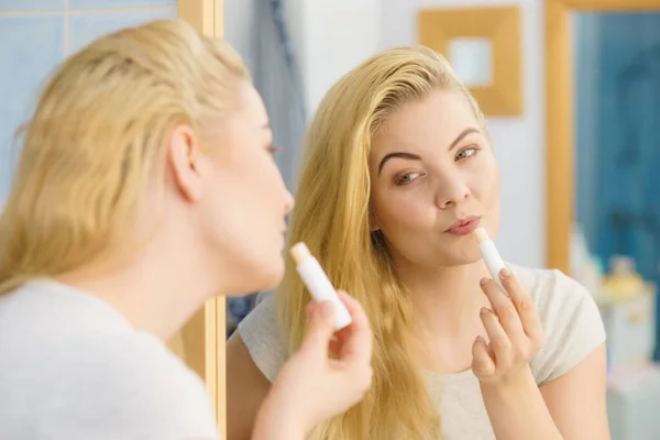 Mujer en baño aplicando bálsamo labial — Foto de Stock