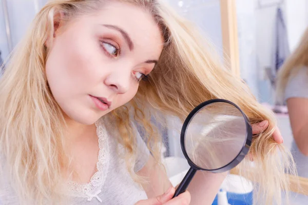 Mulher olhando para o cabelo termina através de lupa — Fotografia de Stock