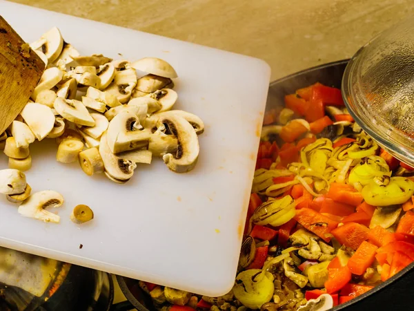 Ajouter des champignons à la casserole de légumes . — Photo