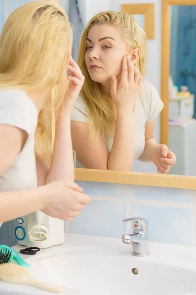 Mujer mirando su piel en el espejo — Foto de Stock