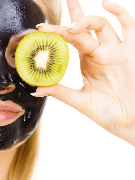 Девушка черная маска на лице держит фрукты киви — стоковое фото