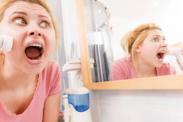 Mujer conmocionada usando cepillo de limpieza facial — Foto de Stock