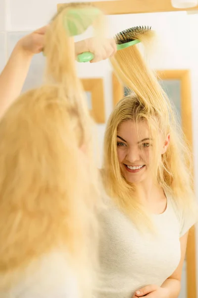 Kvinna borsta sitt blonda hår i badrum — Stockfoto