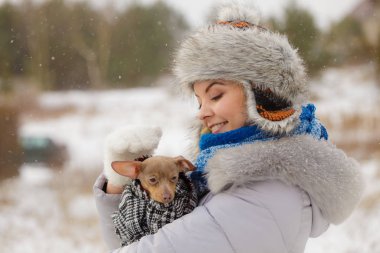 Küçük köpeğini kışın ısınma kadın kucaklama