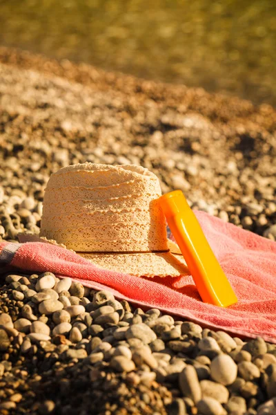 Zonnehoed en zonnebrandcrème op Stone Beach — Stockfoto