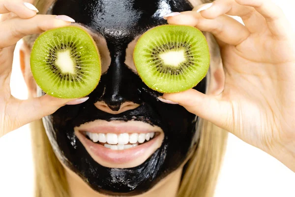 Meisje zwart masker op gezicht houdt Kiwi fruit — Stockfoto