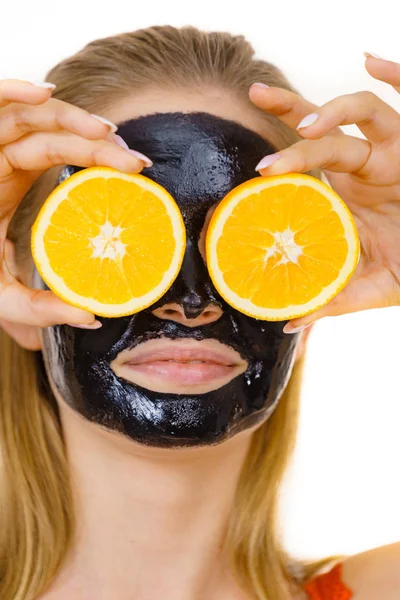 Menina máscara de carbo preto no rosto detém fruta laranja — Fotografia de Stock