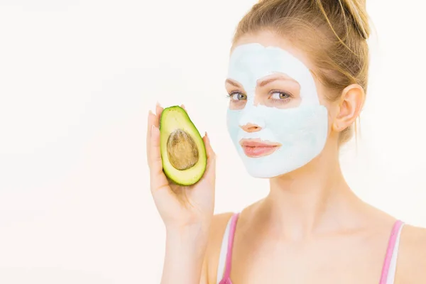 Meisje gezicht modder masker houdt avocado fruit — Stockfoto