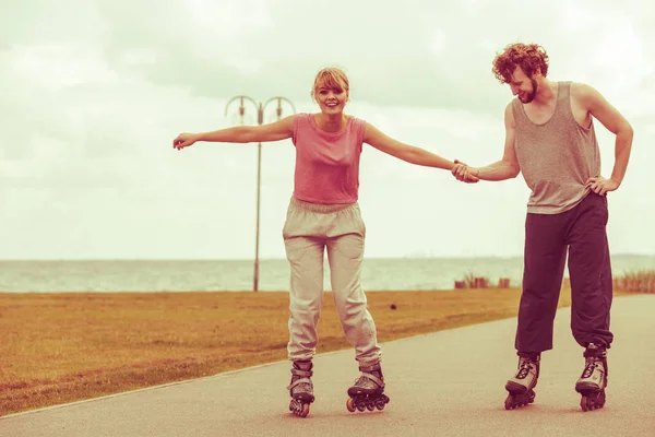 Giovane coppia tenendosi per mano mentre rollerblading — Foto Stock