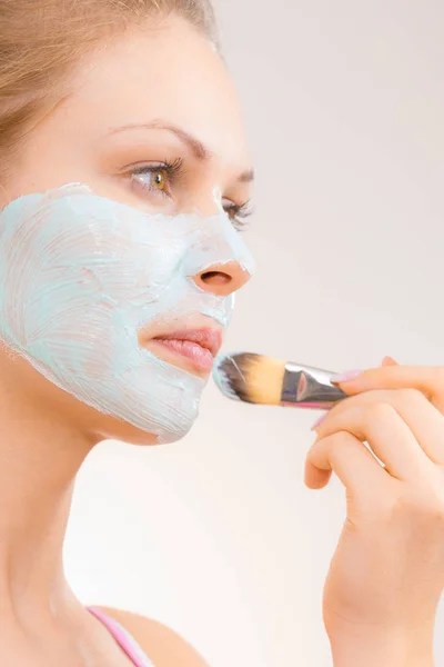 Girl apply green mud mask to face