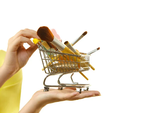 Mujer sosteniendo carrito de compras con pinceles de maquillaje —  Fotos de Stock