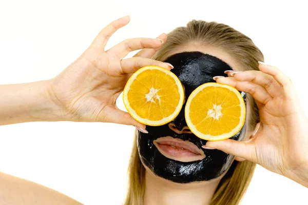 Girl black carbo mask on face holds orange fruit — Stock Photo, Image