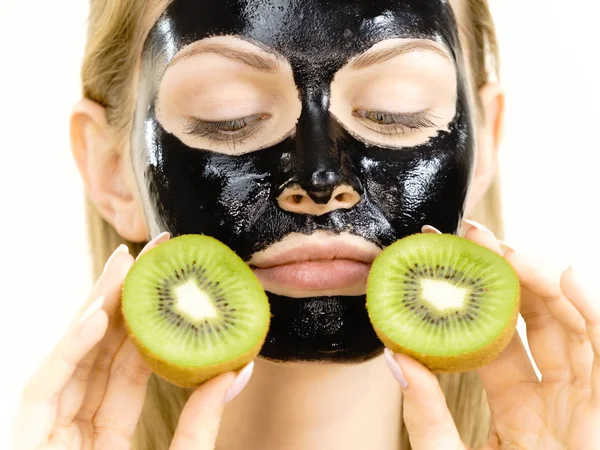 Meisje zwart masker op gezicht houdt Kiwi fruit — Stockfoto