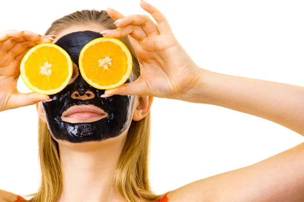 Girl black carbo mask on face holds orange fruit — Stok Foto