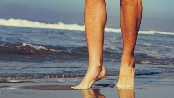 Piernas femeninas en playa de arena — Foto de Stock