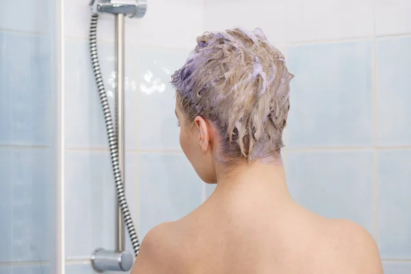 Frau unter der Dusche mit farbigem Schaum auf dem Haar — Stockfoto